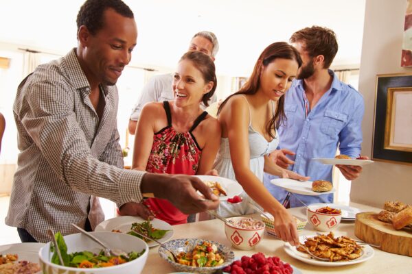 Group of people gathered around a buffet table holding plates.