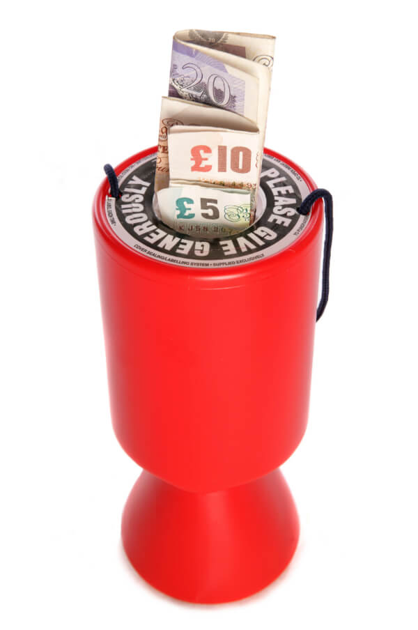 A charity donations tin with £5 and £10 notes sticking out